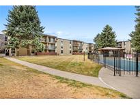 View of the apartment complex featuring mature trees, a pool, and balconies at 2281 Vaughn # 104A, Aurora, CO 80014
