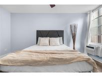 Comfortable bedroom featuring a gray headboard, cozy bedding, and natural light from the window at 2281 Vaughn # 104A, Aurora, CO 80014