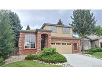 Charming two-story home featuring a brick facade, manicured lawn, and an attached two-car garage at 10538 Tiger Chase, Lone Tree, CO 80124