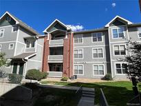 Attractive condo building with gray siding, brick accents, and well-maintained landscaping at 14201 E 1St Dr # 104, Aurora, CO 80011