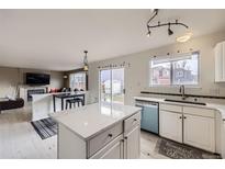 Bright kitchen features white cabinets, an island with seating, and stainless steel appliances at 19372 E 41St Ave, Denver, CO 80249