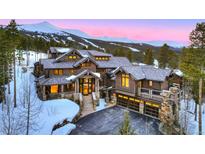 Stunning log home featuring a stone base, grand entrance, and a heated driveway with a backdrop of snow-capped mountains at 422 Timber Trail Rd, Breckenridge, CO 80424