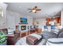 Cozy living room features a stone fireplace, hardwood floors, and comfortable seating arrangements at 16022 W 63Rd Ln # A, Arvada, CO 80403