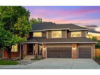 Charming two-story home featuring a two-car garage and a beautiful brick and wood facade against a colorful evening sky at 7873 Sweet Water Rd, Lone Tree, CO 80124