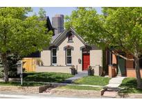 Charming home featuring a well-kept front yard, red door, and beautiful architecture against a downtown skyline at 2355 N Emerson St, Denver, CO 80205
