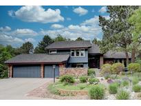 Stunning two-story home featuring lush landscaping, a stone accent wall, and a two car garage at 7715 S Hudson Ct, Centennial, CO 80122
