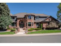 Stately brick home featuring a tile roof, manicured landscaping, and a welcoming entrance at 1193 Phipps Ct, Highlands Ranch, CO 80126
