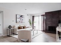 Bright living room with a stone fireplace and sliding glass doors to the outside balcony at 7395 E Eastman Ave # 202N, Denver, CO 80231