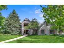 Charming two-story home with brick accents, balcony, lush green lawn, and mature trees at 32 Glenmoor Dr, Englewood, CO 80113
