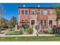 Charming townhome with a red brick facade, front porch, and manicured landscaping under a bright blue sky at 535 Elmhurst Way # A, Highlands Ranch, CO 80129