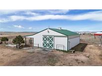 A large barn with white siding, a green metal roof, and a large sliding door with a decorative pattern at 32350 E 137Th Way, Brighton, CO 80603