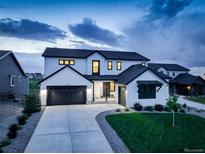 Modern farmhouse exterior with black trim, three-car garage, and manicured lawn at twilight at 39405 Stockton Cir, Elizabeth, CO 80107