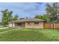 Charming brick home with a well-maintained lawn and mature trees at 7995 Robin Ln, Denver, CO 80221