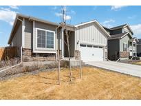 Charming home with a two-car garage, stone accents, and low-maintenance front yard at 17801 E 95Th Pl, Commerce City, CO 80022