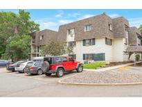 Three-story apartment building featuring white exterior, brown roof, and multiple parked cars in a lot at 5770 E Warren Ave # 206, Denver, CO 80222