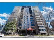 Modern high-rise condo building with balconies against a vibrant blue sky and mature trees at 2 Adams St # 905, Denver, CO 80206