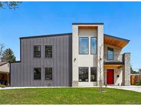 Striking two-story modern home featuring metal and stucco finishes, a balcony, and a bright red front door at 1220 S Elm St, Denver, CO 80246