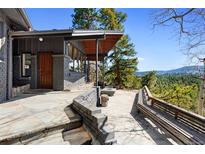 Inviting patio featuring flagstone flooring, stone benches, and a cozy outdoor fireplace with beautiful views at 22598 Westview Ave, Golden, CO 80401