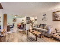 Cozy living room featuring wood-look tile flooring, neutral tones, and comfortable seating area at 3141 S Tamarac Dr # 110G, Denver, CO 80231