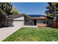 Charming single-story home with a well-manicured lawn and solar panels on the roof at 8559 W 75Th Pl, Arvada, CO 80005