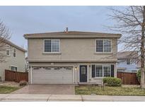 Two-story home with a brick driveway, gray stucco, tile roof, and attached two car garage at 20000 E Mitchell Pl # 39, Denver, CO 80249