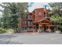 Inviting lodge exterior with wood facade, stone accents, entryway portico and hanging floral baskets at 805 Columbine Rd # 105, Breckenridge, CO 80424