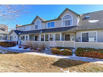 Tan two-story townhome with white trim, small fenced yard, and snow on ground at 1176 E 130Th Ave # C, Thornton, CO 80241