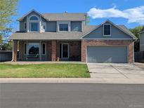 Charming two-story home with brick accents, a covered porch and well-maintained front lawn at 982 E 130Th Cir, Thornton, CO 80241