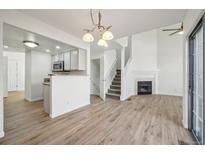 Bright open-concept living area with hardwood floors, fireplace, and updated kitchen featuring stainless steel appliances at 5960 S Jellison St # B, Littleton, CO 80123