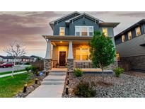 Charming two-story home featuring a welcoming front porch and beautifully landscaped front yard with lovely plantings at 21492 E 60Th Ave, Aurora, CO 80111