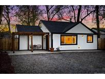 Charming home exterior at twilight with black trim, pergola, and seating area for relaxing outdoors at 1755 Ingalls St, Lakewood, CO 80214