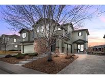 Inviting two-story home featuring a stone facade, mature landscaping, and a driveway leading to a two-car garage at 12941 Grant W Cir # C, Thornton, CO 80241