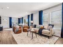 Bright living room with wood floors, tan sofa and blue curtains at 5202 Reed St, Arvada, CO 80002