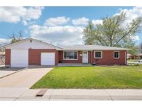 Charming red brick ranch-style home featuring an attached two-car garage and a well-maintained lawn at 6086 W Arizona Ave, Lakewood, CO 80232