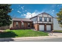 Charming two-story home with brick accents, a well-manicured lawn, and an attached two-car garage at 15930 E Ford Pl, Aurora, CO 80017