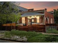 Charming brick home with string lights, a wooden fence, and a cozy front porch at sunset at 3914 Osage St, Denver, CO 80211