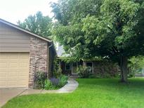 Charming brick home with a lush green lawn, mature trees, and a welcoming walkway to the front door at 12631 W Dakota Dr, Lakewood, CO 80228