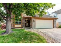 Charming brick home with a well-maintained lawn and mature shade tree at 9614 W Powers Cir, Littleton, CO 80123