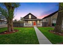Charming home with a red door, welcoming front porch and green lawn surrounded by mature trees at 800 S Krameria St, Denver, CO 80224