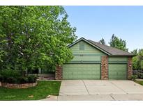 Charming home exterior featuring a two-car garage, stone accents, and a lush, mature tree in the front yard at 2130 Chestnut Cir, Erie, CO 80516