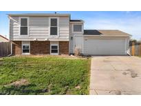 Split level home featuring a two-car garage, brick accents, and a well-maintained front yard at 1488 S Andes Way, Aurora, CO 80017
