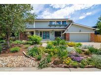 Charming home featuring a landscaped front yard with a mix of colorful flowers and stone accents at 14023 W Alaska Dr, Lakewood, CO 80228