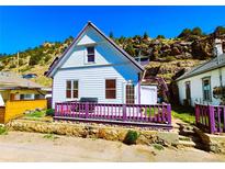Charming home featuring a delightful front porch and unique purple trim accents against the backdrop of the rocky hillside at 1716 Virginia St, Idaho Springs, CO 80452