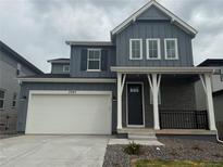 Charming two-story home with a blue exterior, a covered porch, and a two-car garage, set against a cloudy sky at 7267 Prairie Sage Pl, Littleton, CO 80125