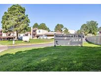 Exterior view of the Woodstream Falls community sign surrounded by lush greenery on a bright day at 9995 E Harvard Ave # 221, Denver, CO 80231