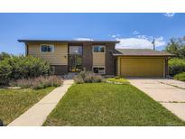 Two-story home with a brick and siding exterior, lush front lawn, and attached garage on a sunny day at 11462 W Tennessee Pl, Lakewood, CO 80226