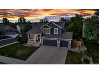 Charming two-story home with a three-car garage and manicured front lawn set against a colorful sunset sky at 12430 S Downy Creek Ct, Parker, CO 80134