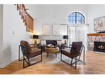 Inviting living room features a stone fireplace, two accent chairs, and stairway access to the second floor at 942 S Walden St # 204, Aurora, CO 80017