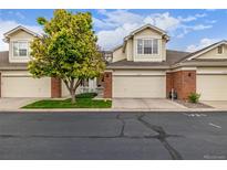 Charming two-story townhome featuring a two-car garage, brick accents, and a well-manicured lawn at 13545 W 62Nd Ln, Arvada, CO 80004