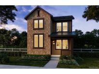 Charming two-story home featuring a mix of stone and siding, large windows, and a landscaped front yard at 8785 Whiteclover St, Littleton, CO 80125